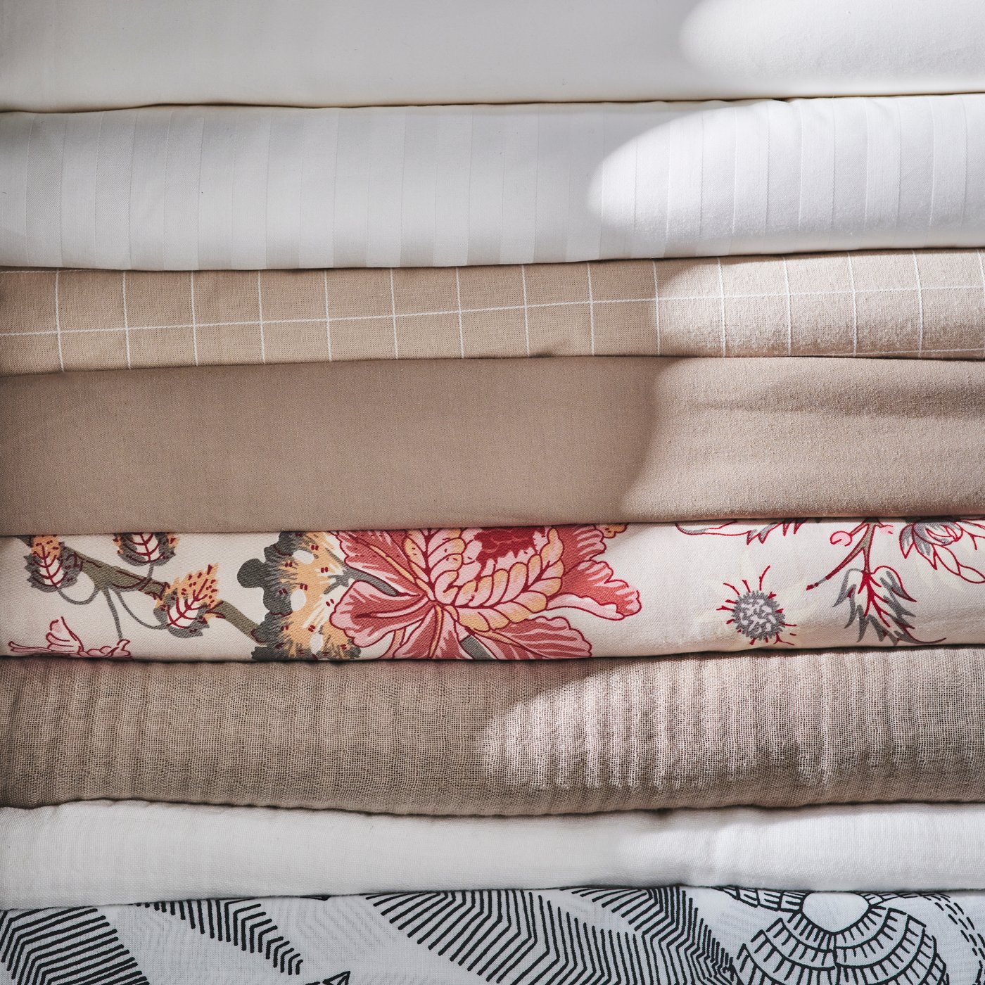 A pile of eight different types of bed linen including white NATTJASMIN and black and white BROKDRACENA bed linen.