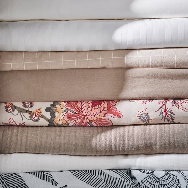 A pile of eight different types of bed linen including white NATTJASMIN and black and white BROKDRACENA bed linen.