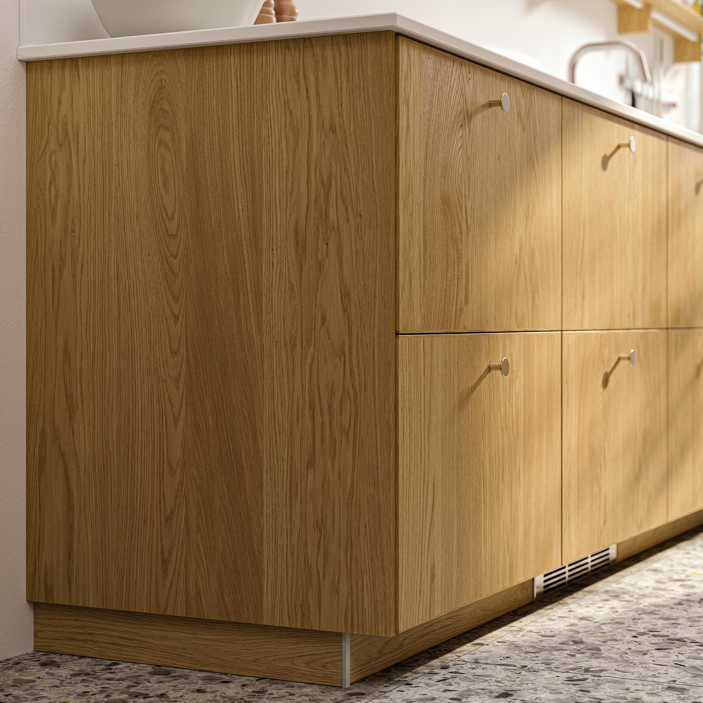 Primo piano di alcuni mobili METOD con frontali e rivestimenti SINARP in impiallacciatura di rovere e pomelli KALERUM color acciaio inox.