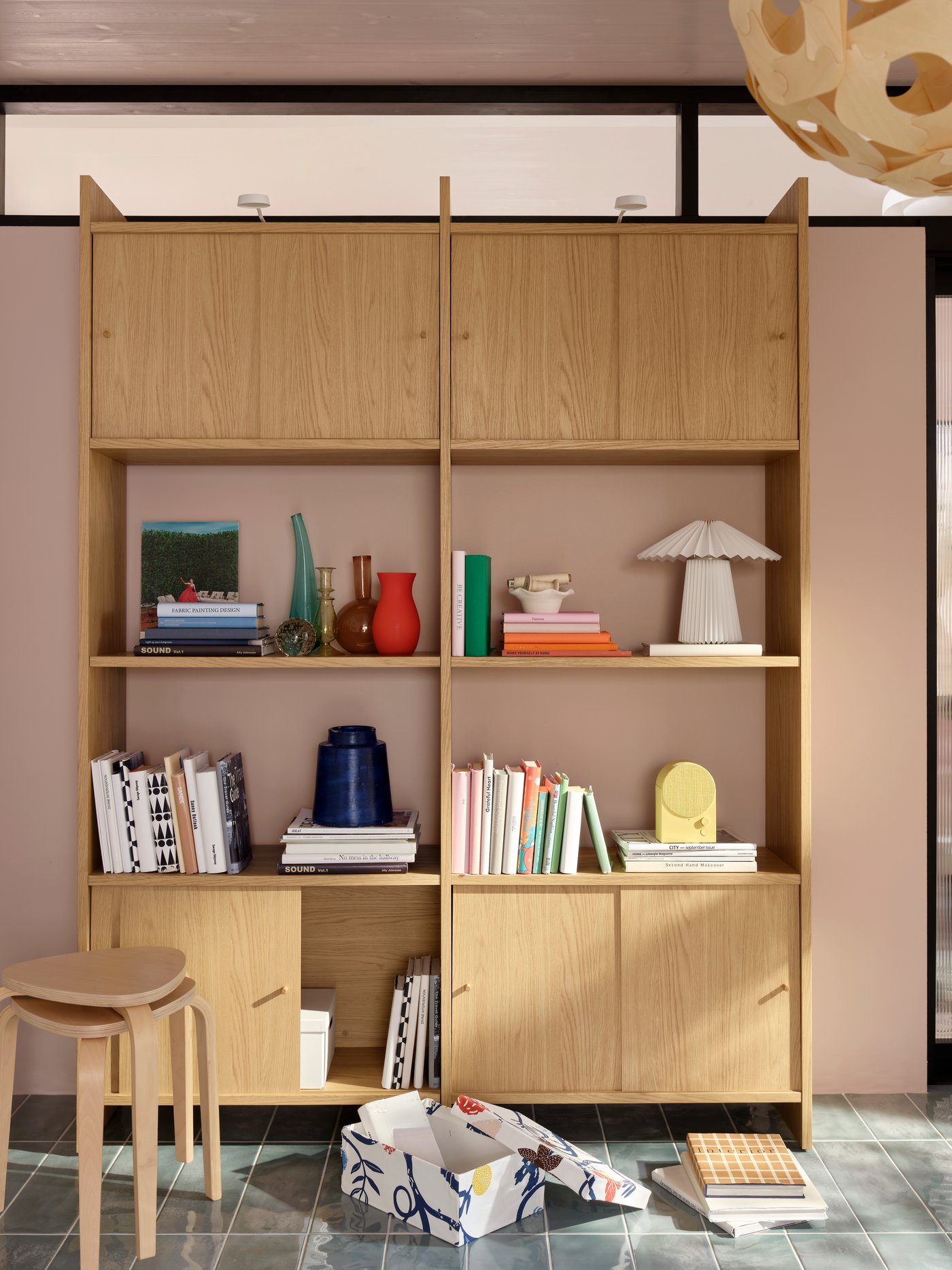A bright living room with a light oak-effect LÅDMAKARE storage combination with sliding doors with books and decoration.