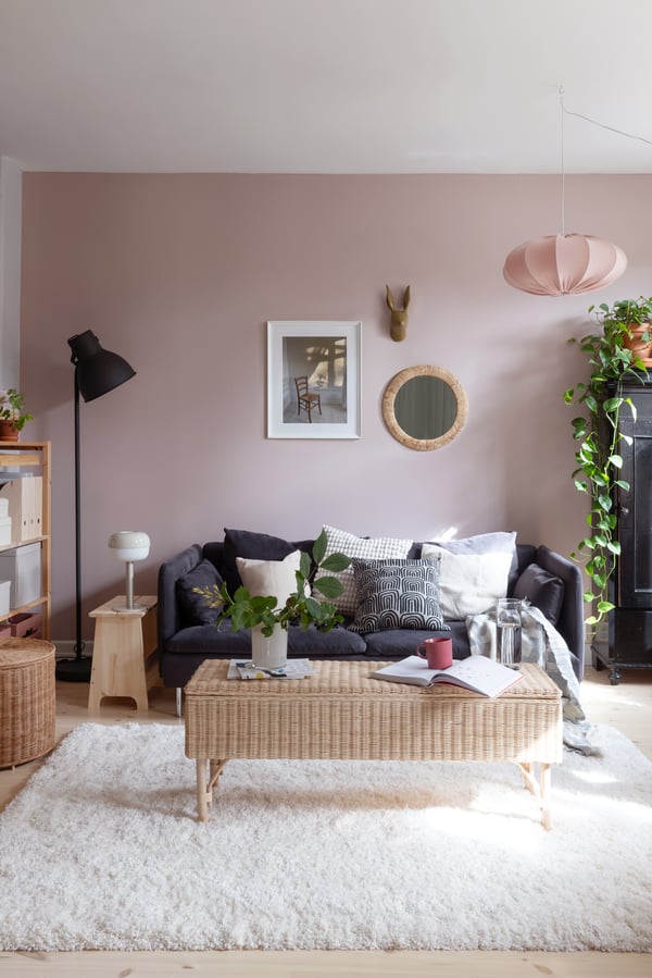 En grå sofa i en dus rosa stue med masse bra oppbevaring.