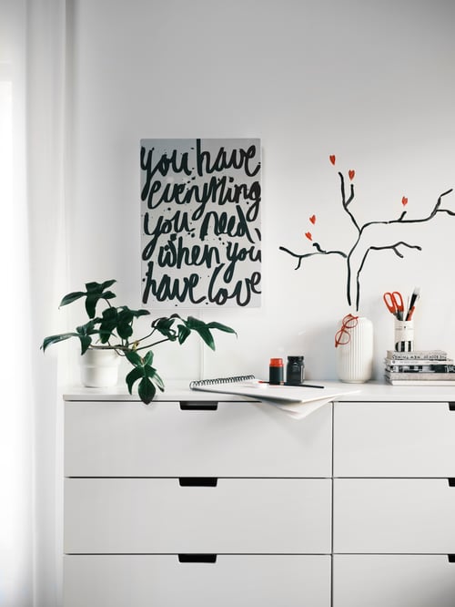 An der Wand über einer NORDLI Kommode hängt ein SYMFONISK Paneel für Rahmen mit Speaker. Auf der Kommode ist auch eine STILREN Vase zu sehen.
