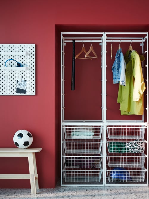 Hallway with various clothing items in a JONAXEL wardrobe combination, a soccer ball on a bench, and a pegboard combination.