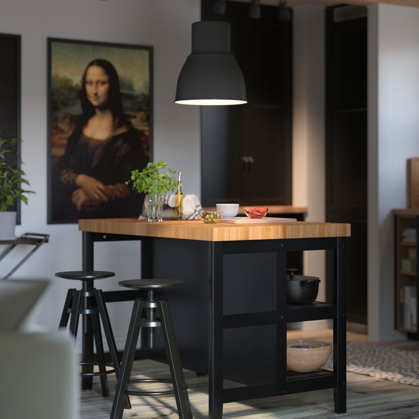 En VADHOLMA köksö i svart och ek med en svart hänglampa ovanför och två pallar i ett vitt kök med bjälkar.