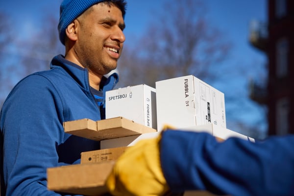A person in a blue shirt is giving flatpcks to the other co-worker. 