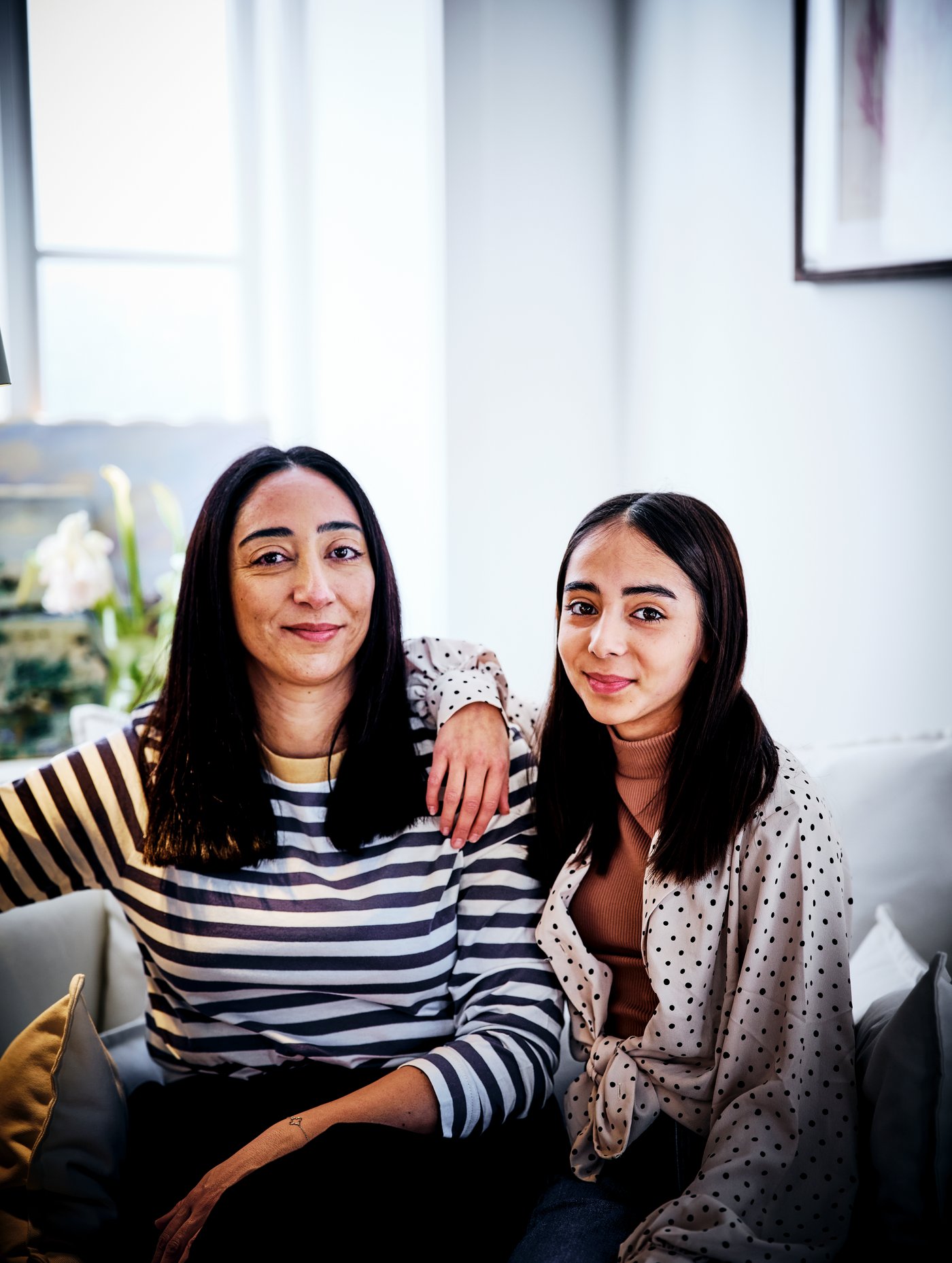 Młoda dziewczyna siedząca ze swoją mamą na sofie.