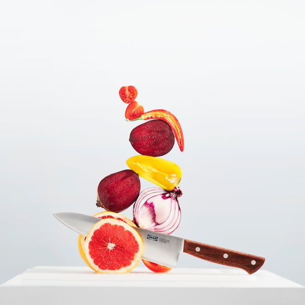 Ein VARDAGEN Messer schneidet durch eine Grapefruit. Obenauf sind weitere Gemüsesorten gestapelt.