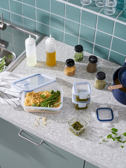 A worktop with big and small IKEA 365+containers filled with food, next to IHÄRDIG spice jars and GRILLTIDER squeeze bottles.