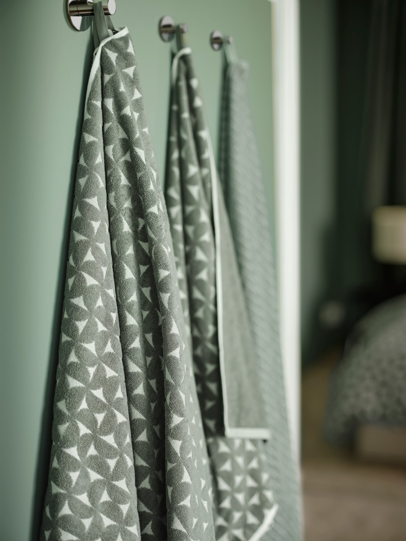 Dettaglio di due asciugamani verdi a fantasia ÄNGSNEJLIKA.