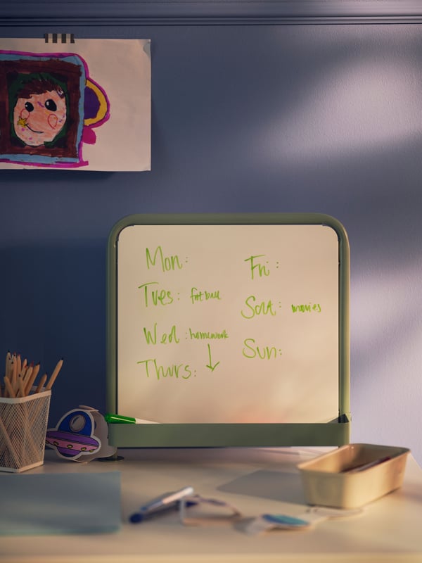 A light grey-green RELATERA writing board and a green MÅLA whiteboard pen beside a NOJIG organiser holding more pens.