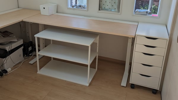 ナチュラルな木目のデスクと、収納ボックスやラックがある。