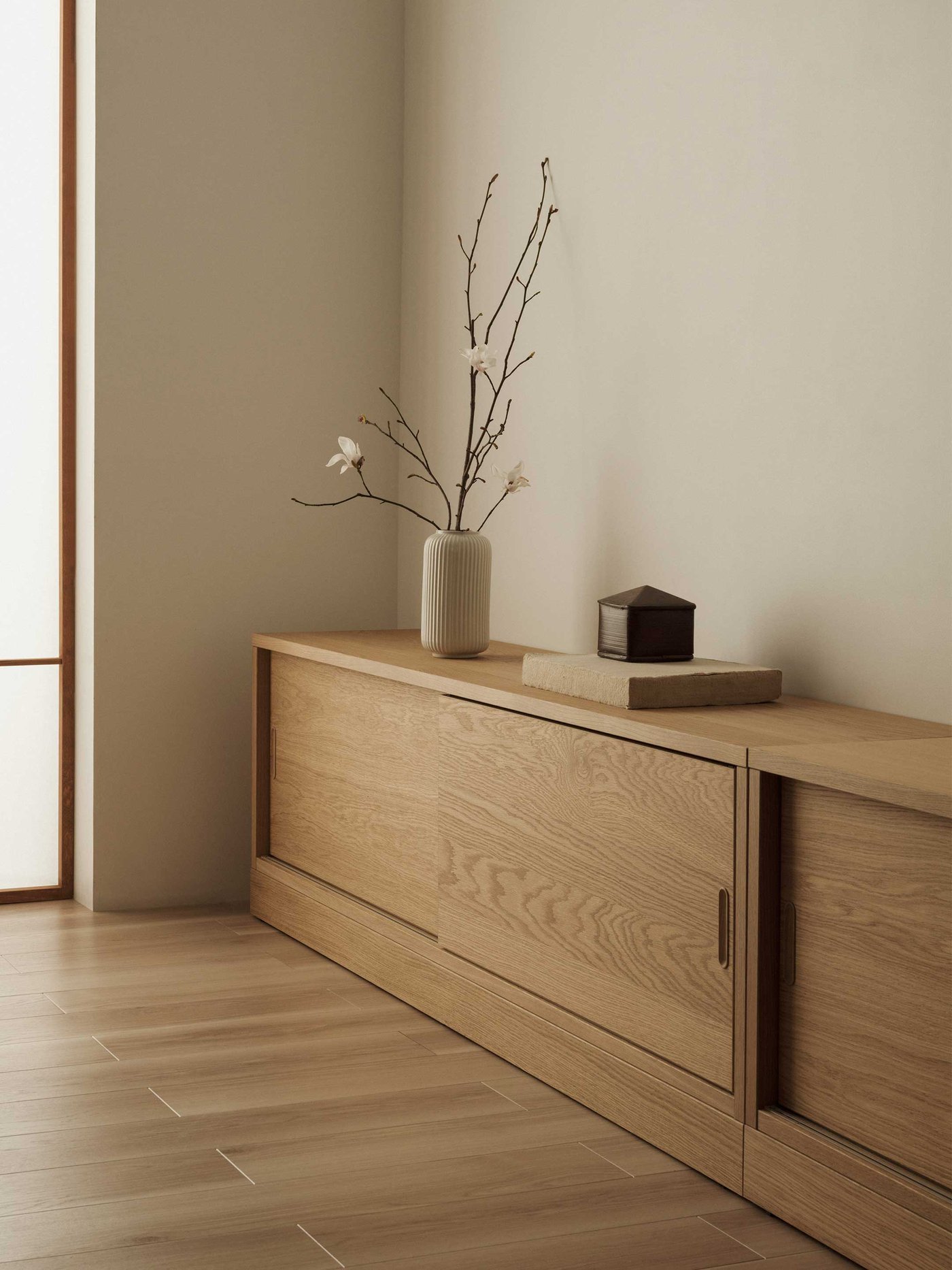 Een Japandi woonkamer met een eikenfineer TONSTAD tv-meubel met daarop decoratie zoals een vaas met een tak erin.