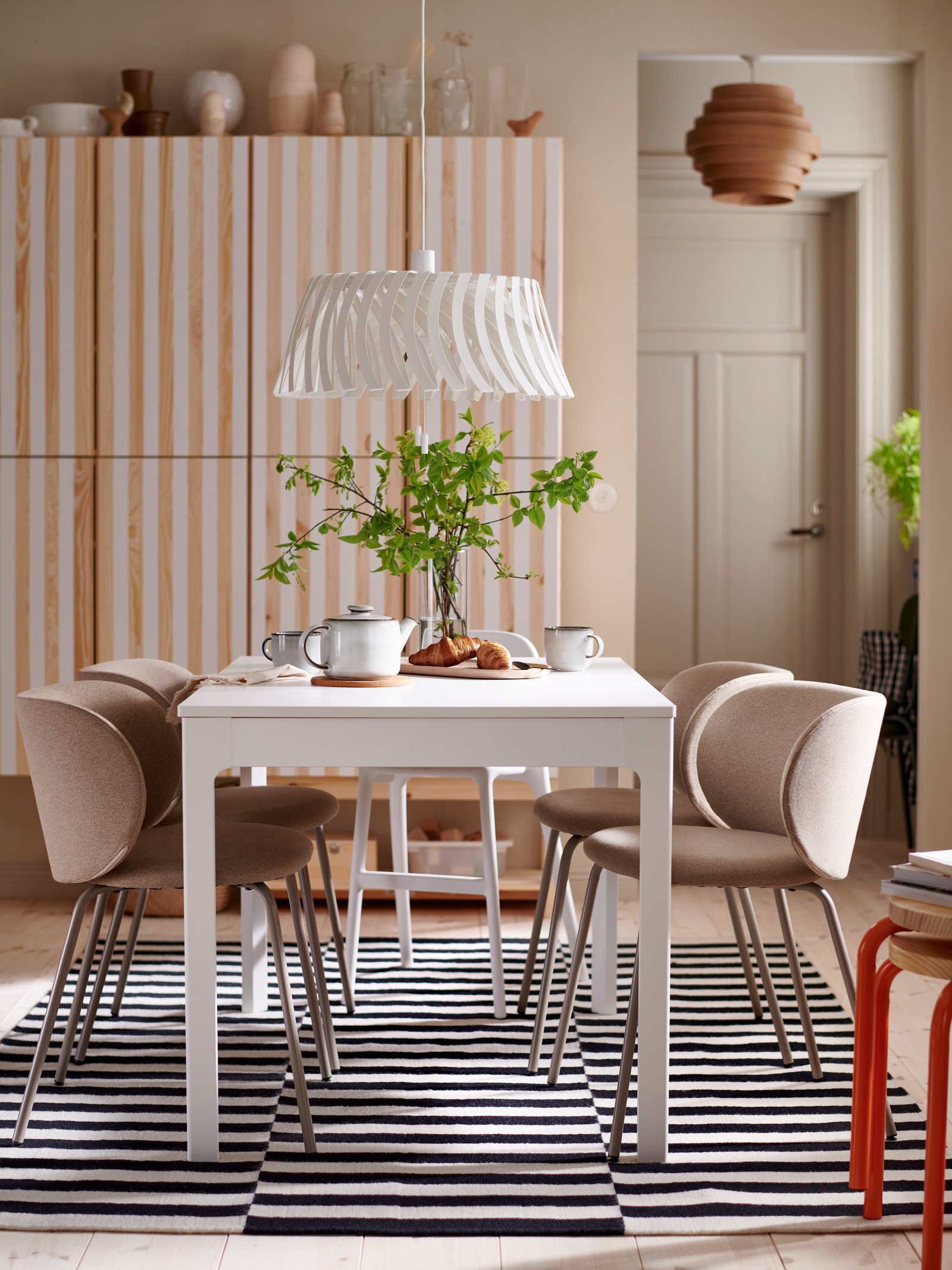 O masă extensibilă EKEDALEN, cu patru scaune KRYLBO și un scaun junior URBAN în jurul său, se află într-o sufragerie.