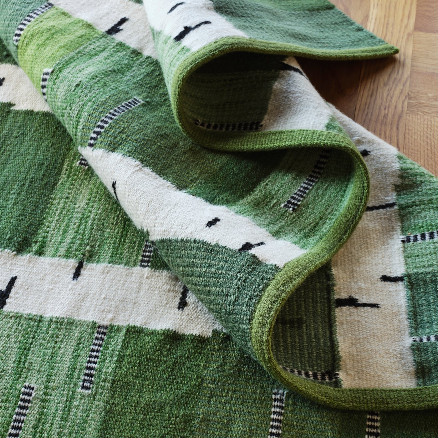 A green/white/black handwoven STOCKHOLM 2025 rug, flatwoven