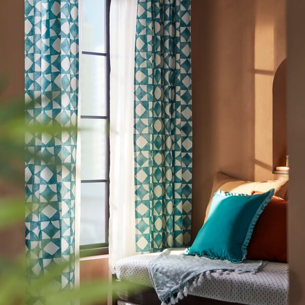 A pair of GOKVÄLLÅ curtains hanging on windows with sunlight filtering through