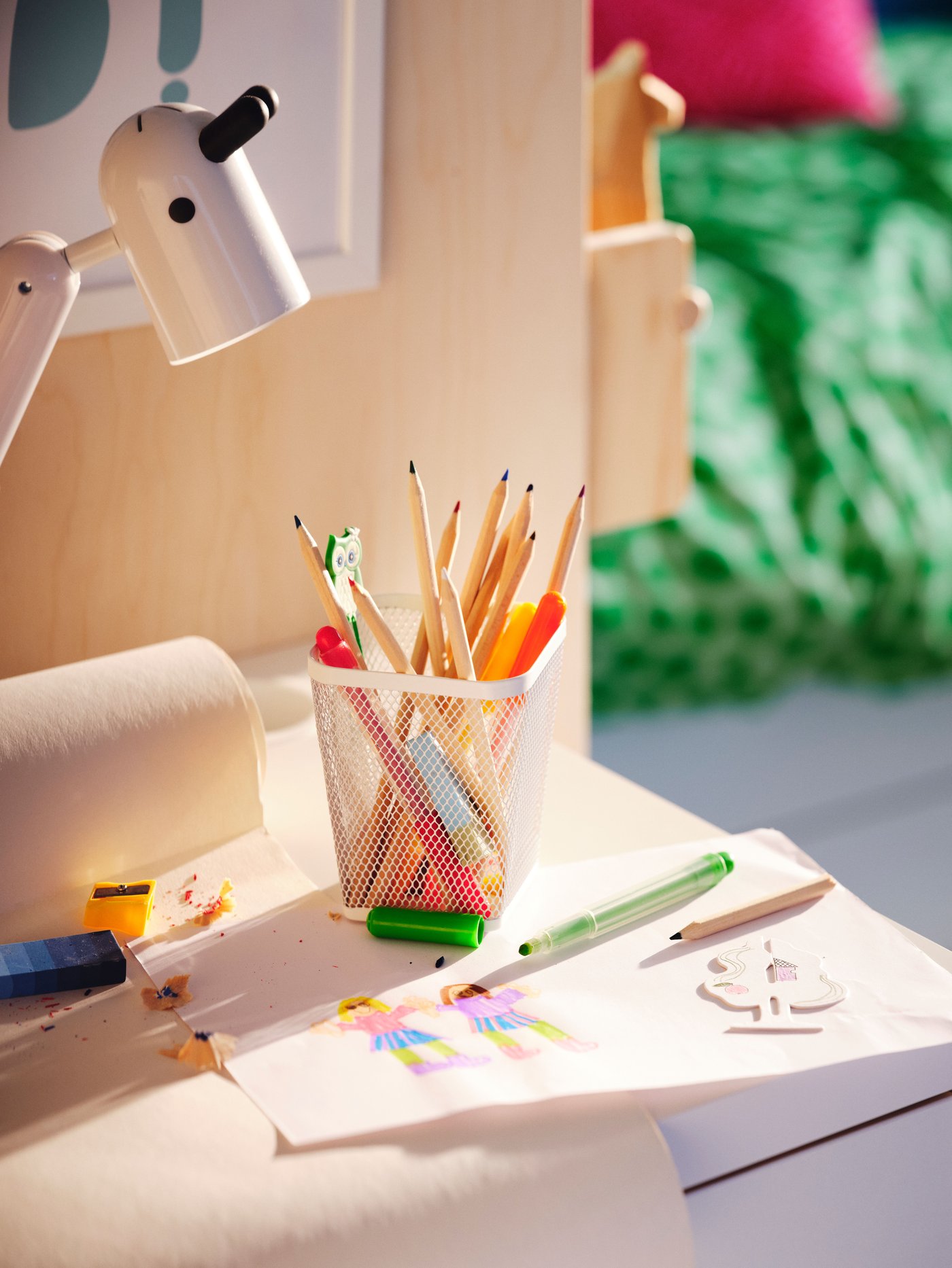 Close-up of a desk with MÅLA pencils and a colourful drawing with two friends holding hands.