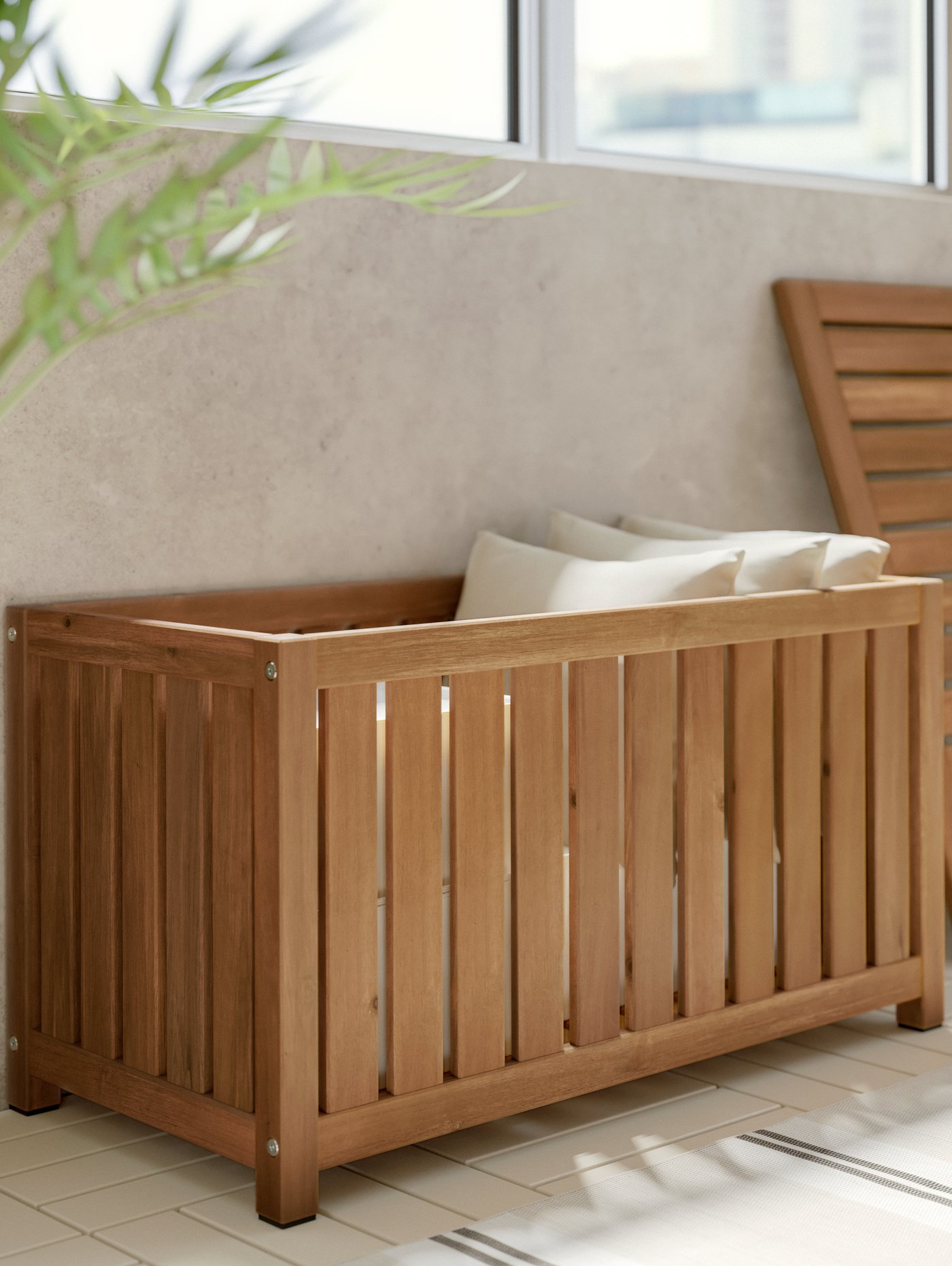 Una caja de almacenaje de madera NÄMMARÖ con cojines blancos IKEA en el interior.