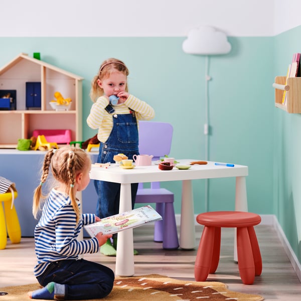 Twee kinderen spelen naast een witte MAMMUT tafel en een rode MAMMUT kruk