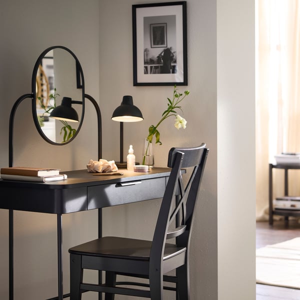 A GRÅFJÄLLET dressing table in anthracite with INGOLF chair in brown-black in front, placed in corner of a room.