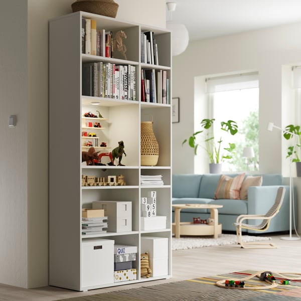 A white TJENA storage box with lid in a tall white shelving unit