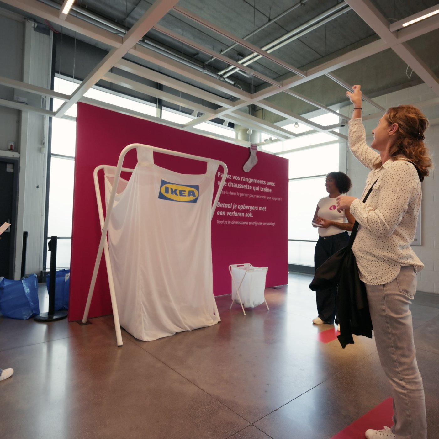Een IKEA-shirt hangt aan een frame voor een roze actieachtergrond terwijl een deelnemer een sok naar het doel werpt.