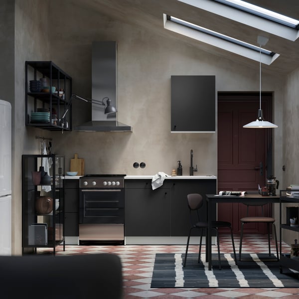 A dark grey KNOXHULT wall cabinet with a door is displayed in a modern kitchen setting, accompanied by a stylish décor.