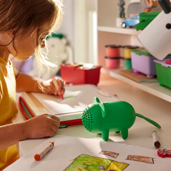 Green mouse-shaped GREJSIMOJS portable Bluetooth speaker being used by a child during playtime.