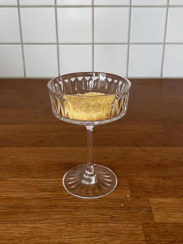 En SÄLLSKAPLIG champagnecoupe med en bit tårtbotten i. 
