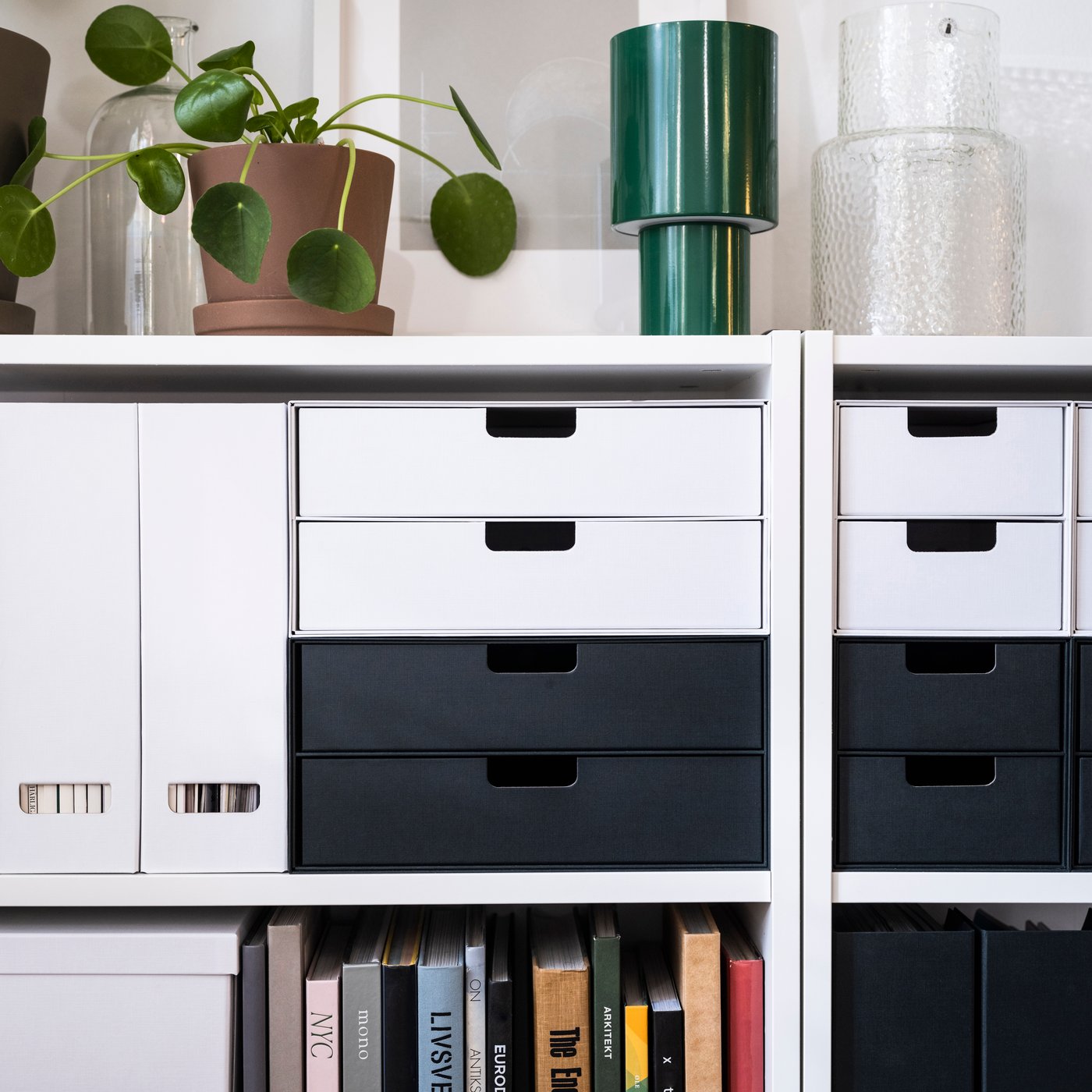 A cabinet in the home office with white and black FJÄDERHARV mini drawer units for office supplies.