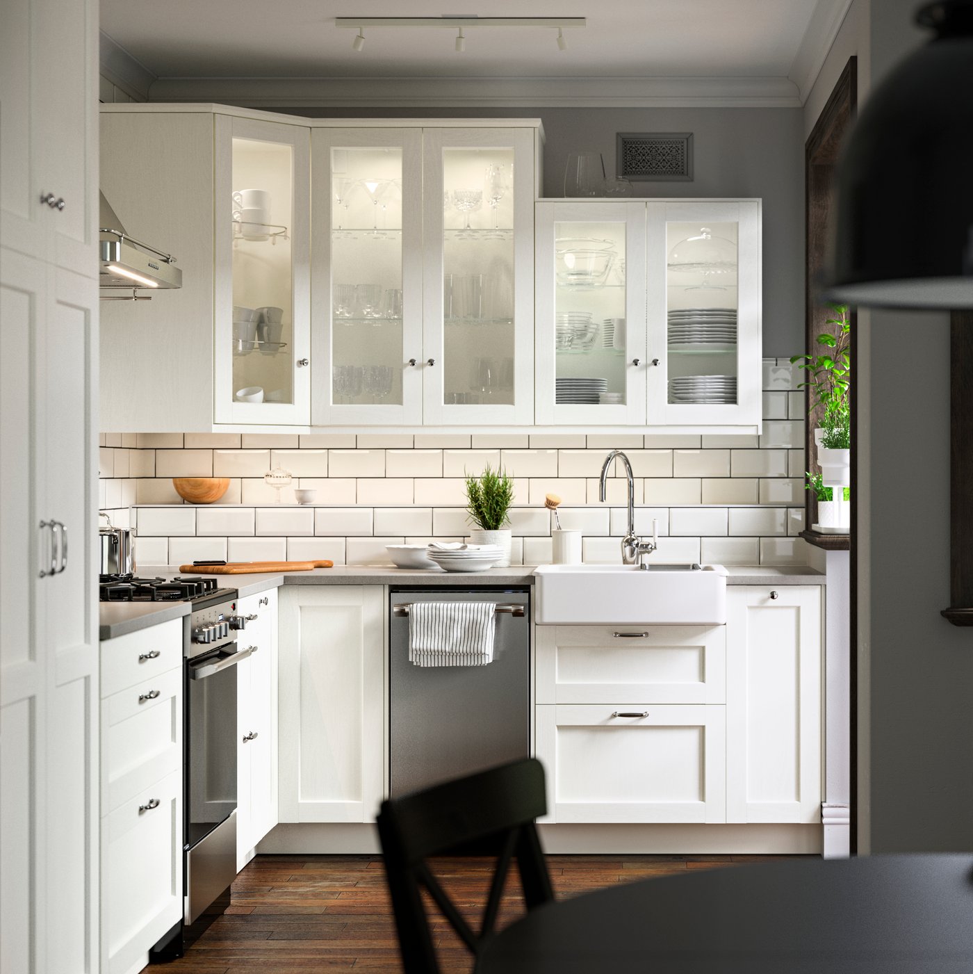 A kitchen with ENKÖPING white fronts, a CIRKULERA range in stainless steel, a HAVSEN sink bowl and a SVARTNORA pendant lamp.