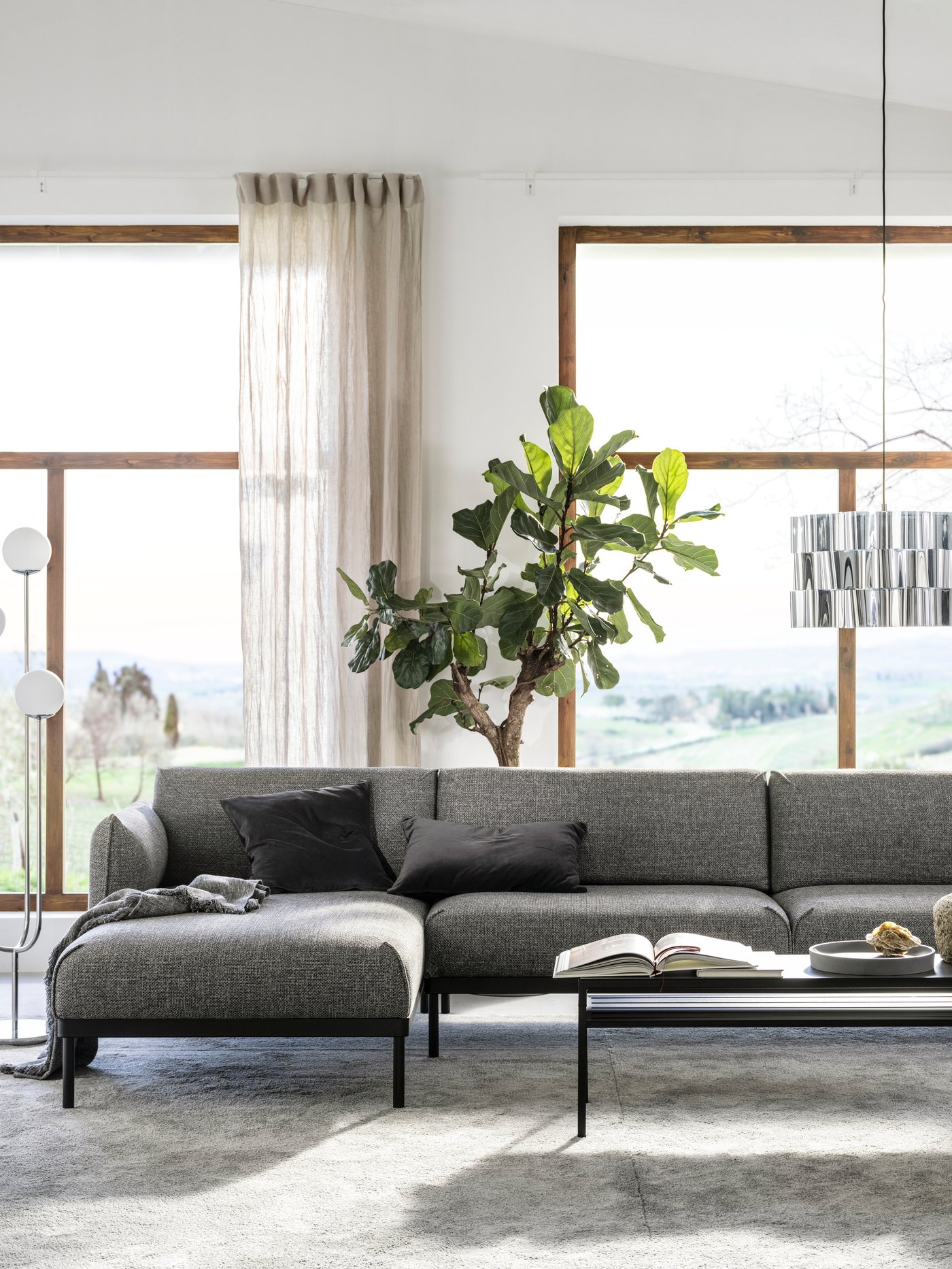 Salón con un sofá de 4 plazas con chaise longue con muelles ensacados interiores junto a una mesa de centro con tablero reversible.
