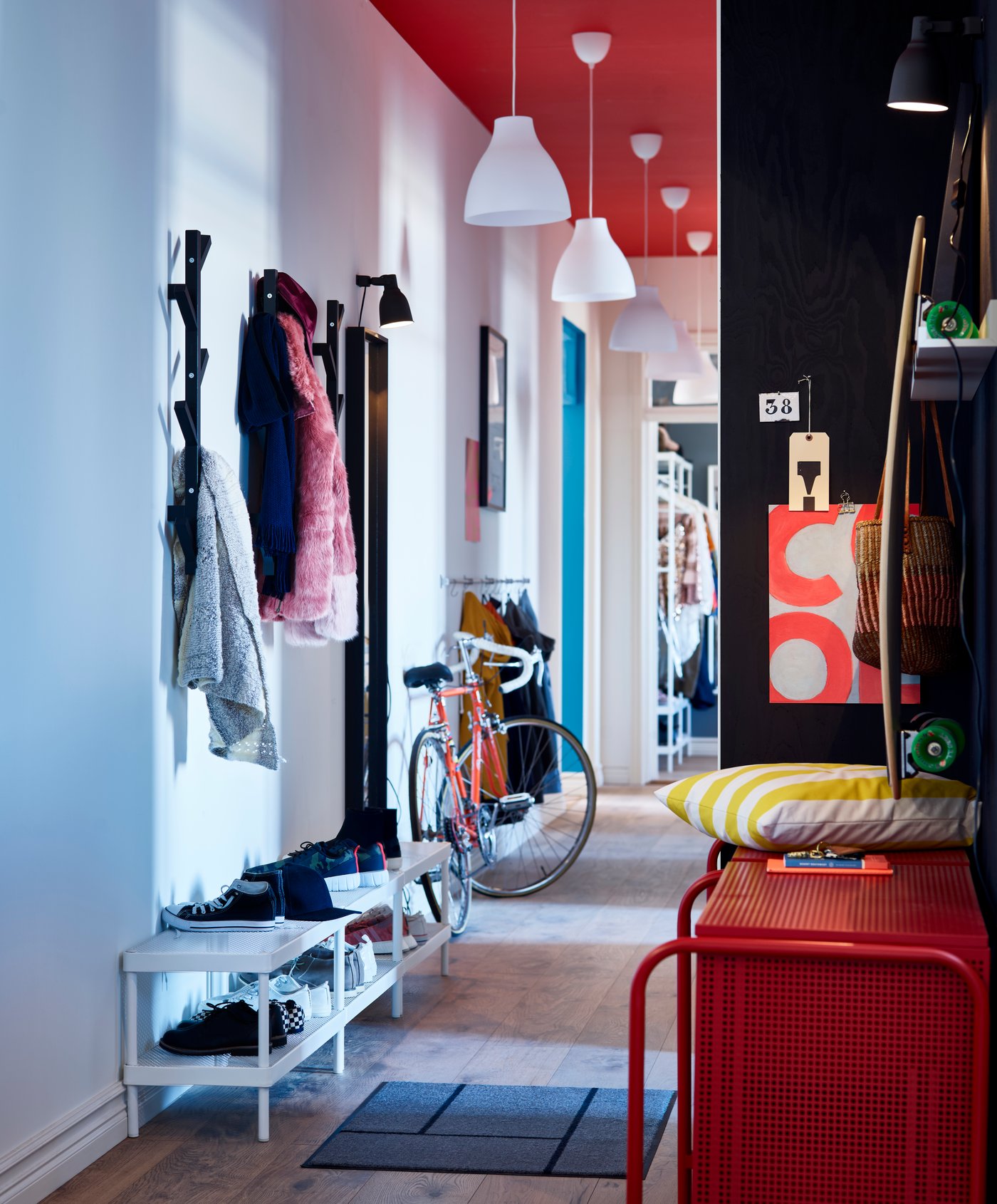 Een hal met een grijs KÖGE deurmat naast een rode NIKKEBY ladekast.