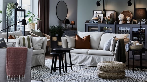 A natural-toned living room with a BACKSÄLEN two-seat sofa and large armchair around two black nested coffee tables.