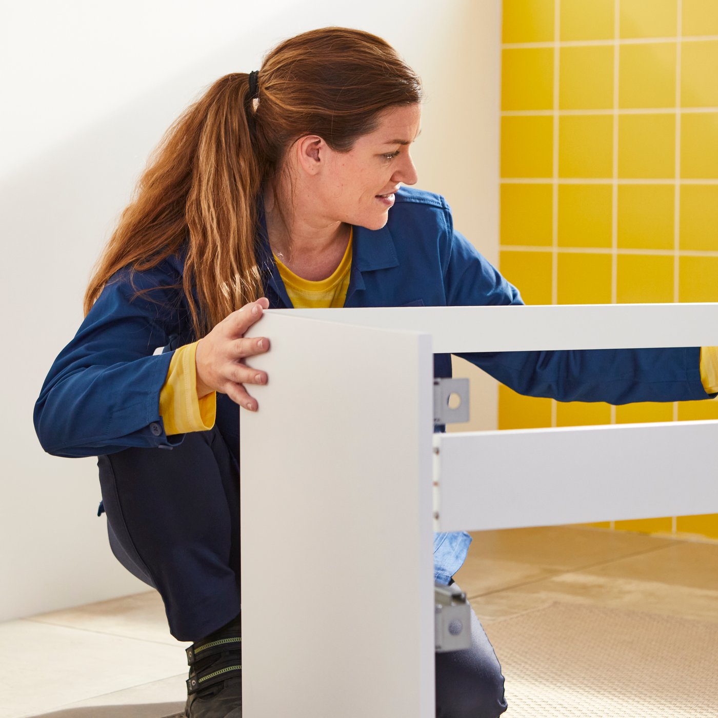 An IKEA installer assembling an IKEA bathroom drawer.