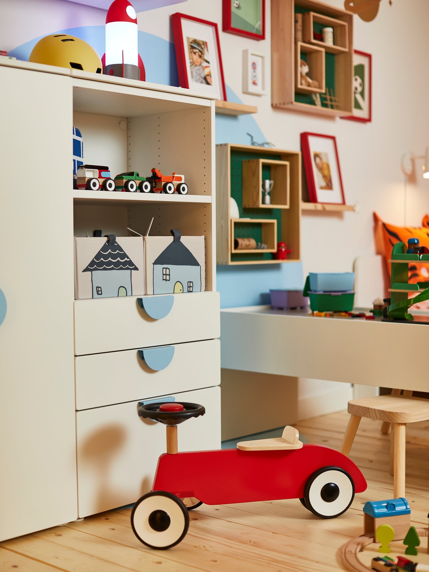Ein Kinderzimmer mit einem weißen Schrank und bunten Accessoires und Spielzeugen.