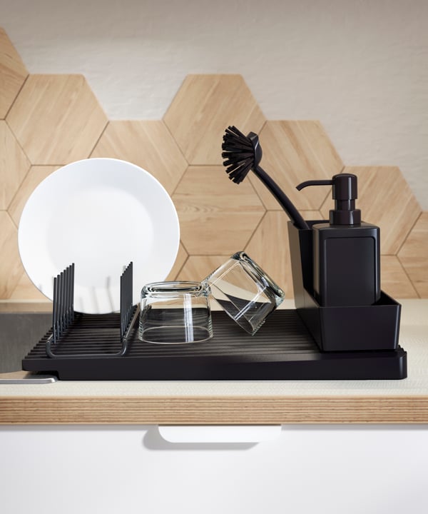 Un porte-vaisselle RINNIG noir rempli de différents accessoires pour laver la vaisselle.