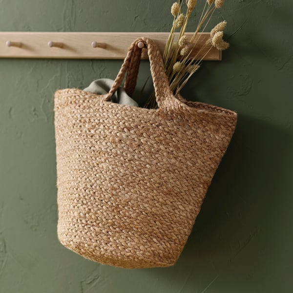 Close up of a TOLKNING jute basket hanging from one of the six knobs of a wooden HÖVOLM rack.