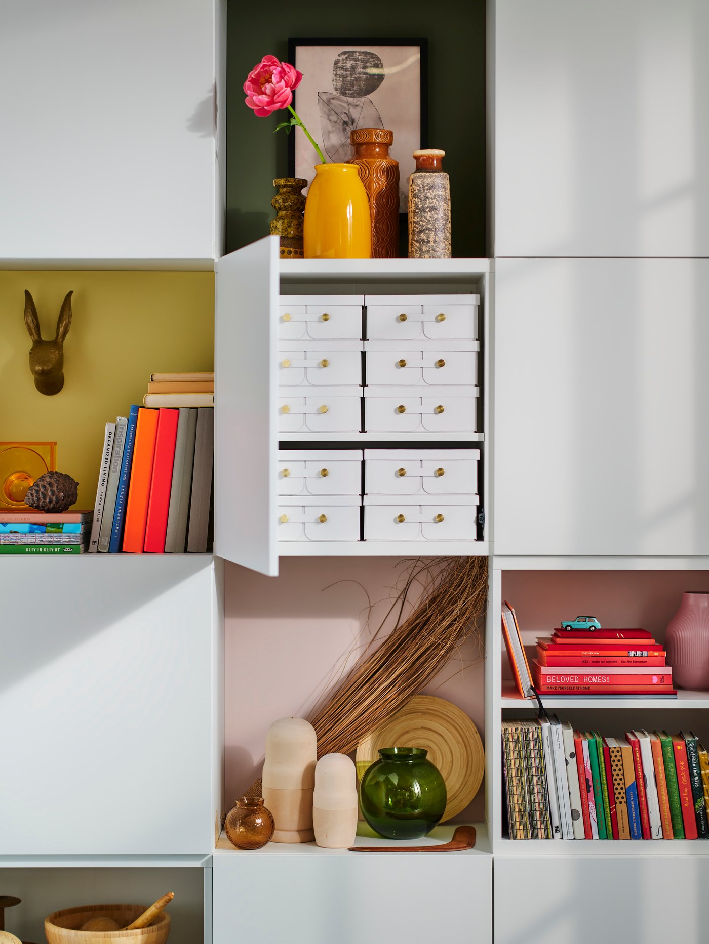 Achter een eettafel staat een boekenkast boordevol interieuraccessoires en opbergruimte.