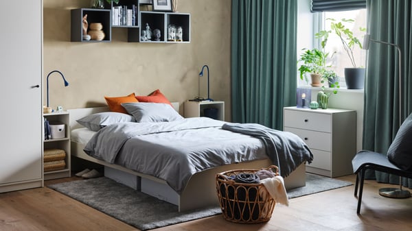 A black NÄVLINGE LED wall/clamp spotlight in the bedroom