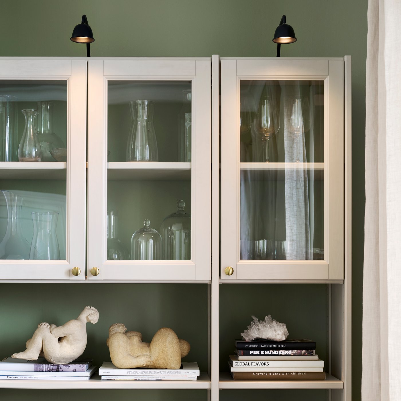 Close-up of GULDDRAGARE glass doors with vases and sculptures inside.