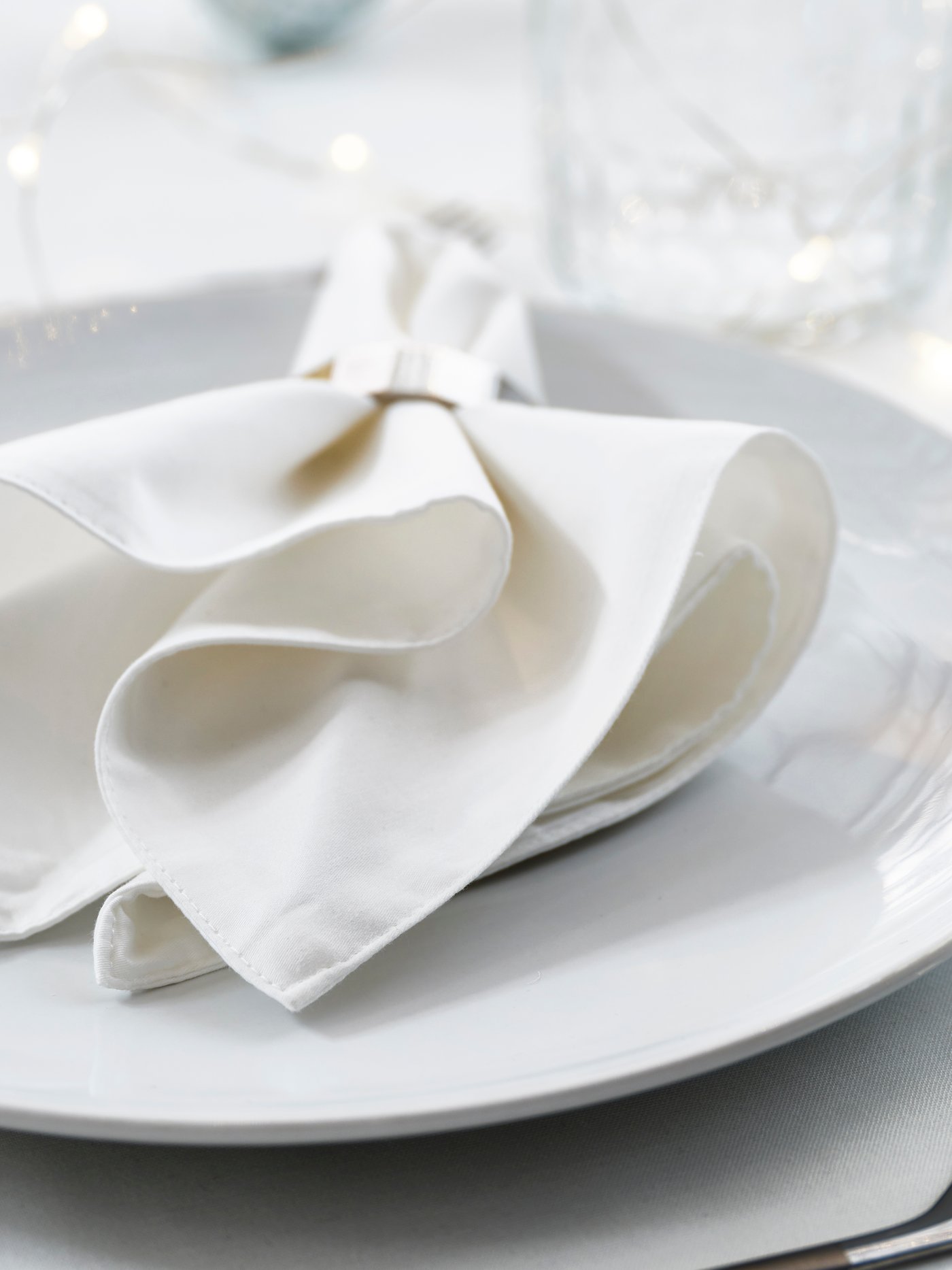 Eine weiße FRÖJDA Stoffserviette auf einem Teller.