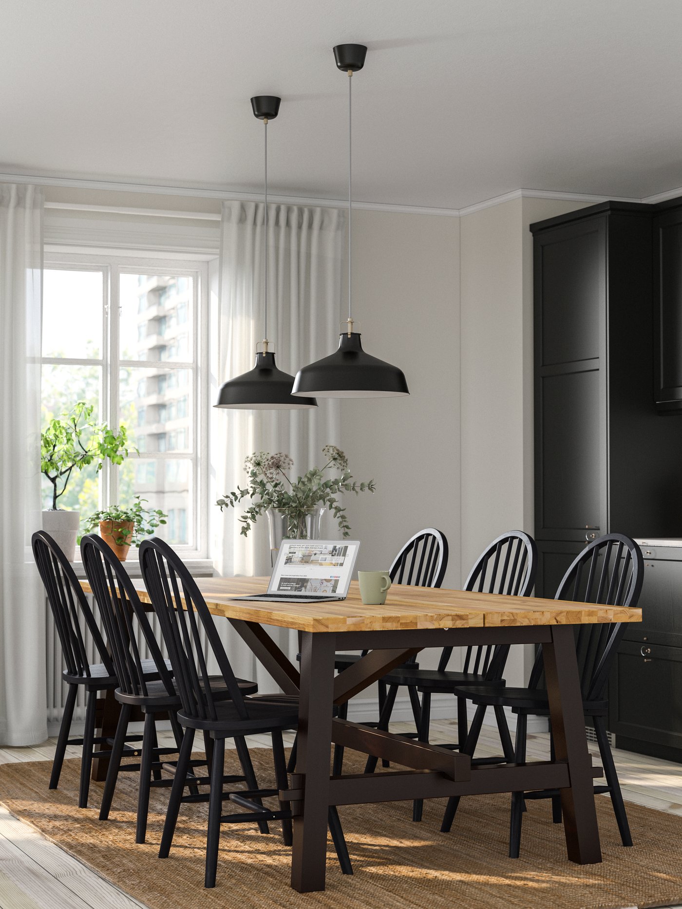 An acacia/black SKOGSTA dining table with black pendant lights