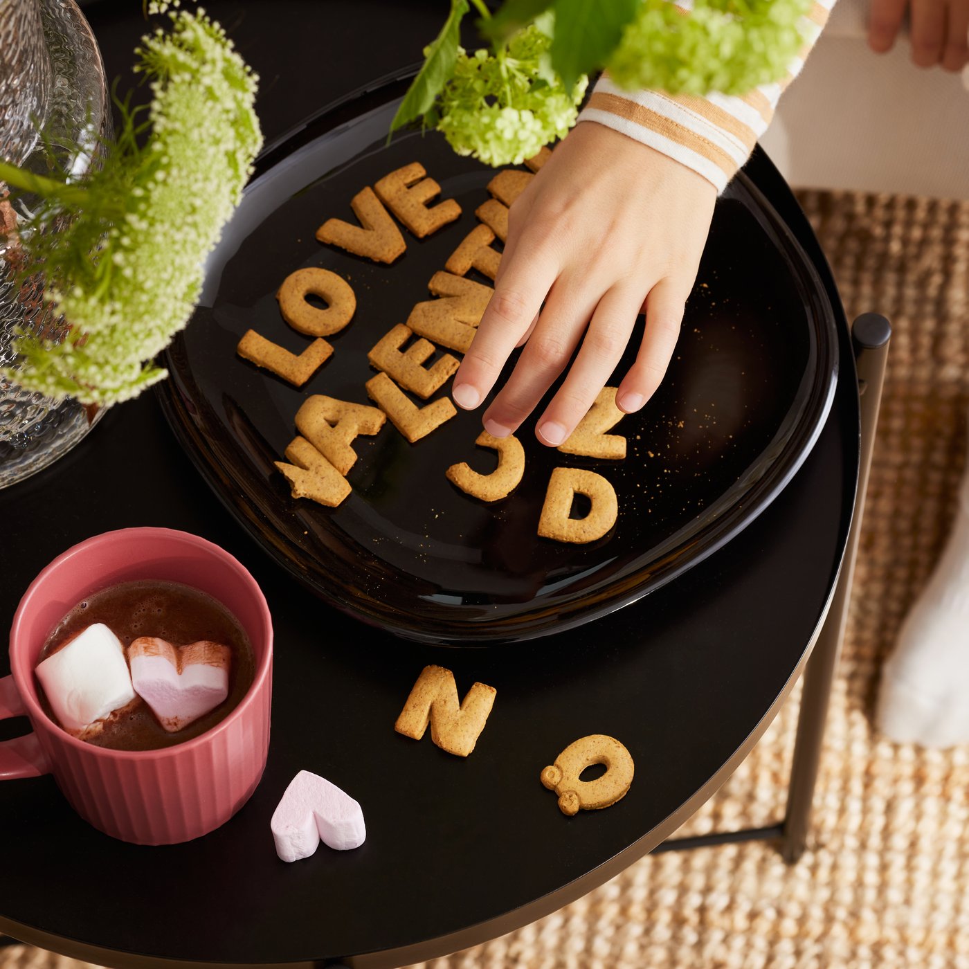 Litery-ciastka układające się w słowo "love" na czarnym stoliku.