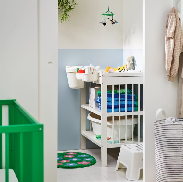 A bright nursery featuring a white GULLIVER changing table, neatly organised with baby essentials and colourful towels.