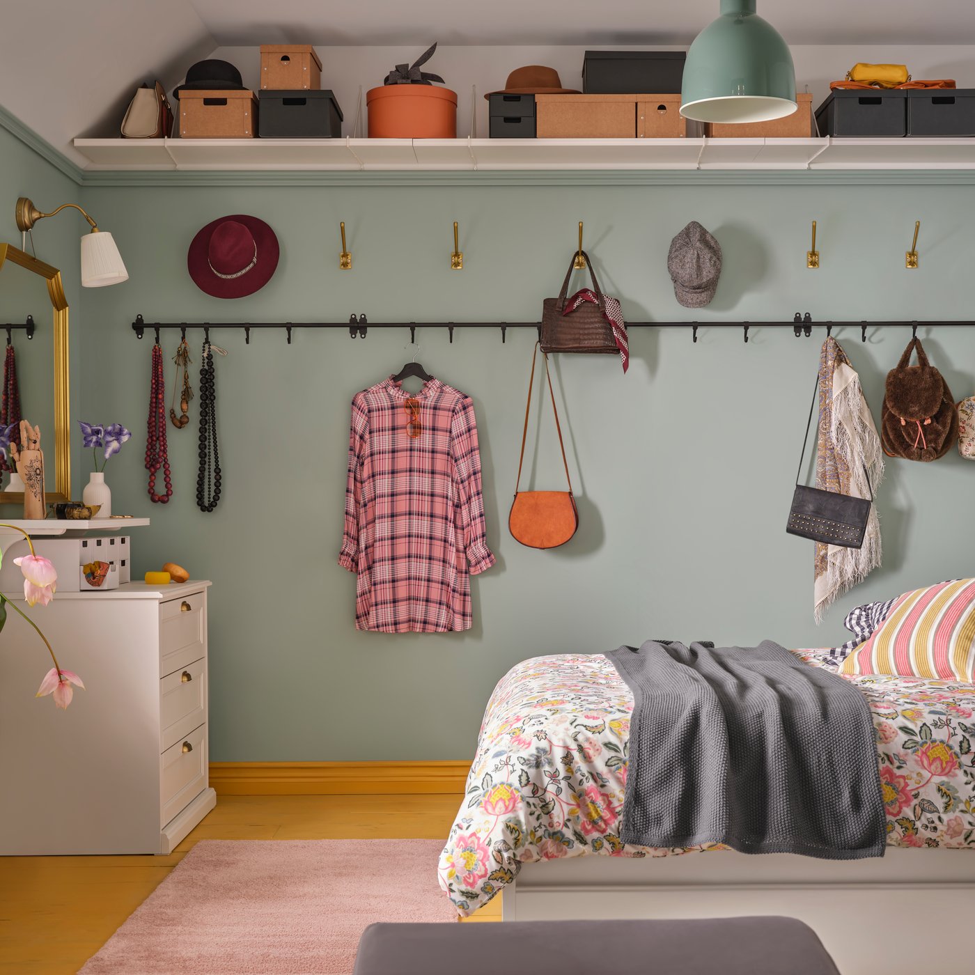 A room with a black HULTARP rail displays bags and accessories on hooks against a green wall, adding stylish storage space.