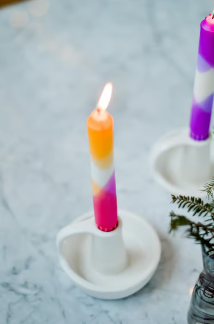 Bunte Kerzen in einem weissen Kerzenhalter