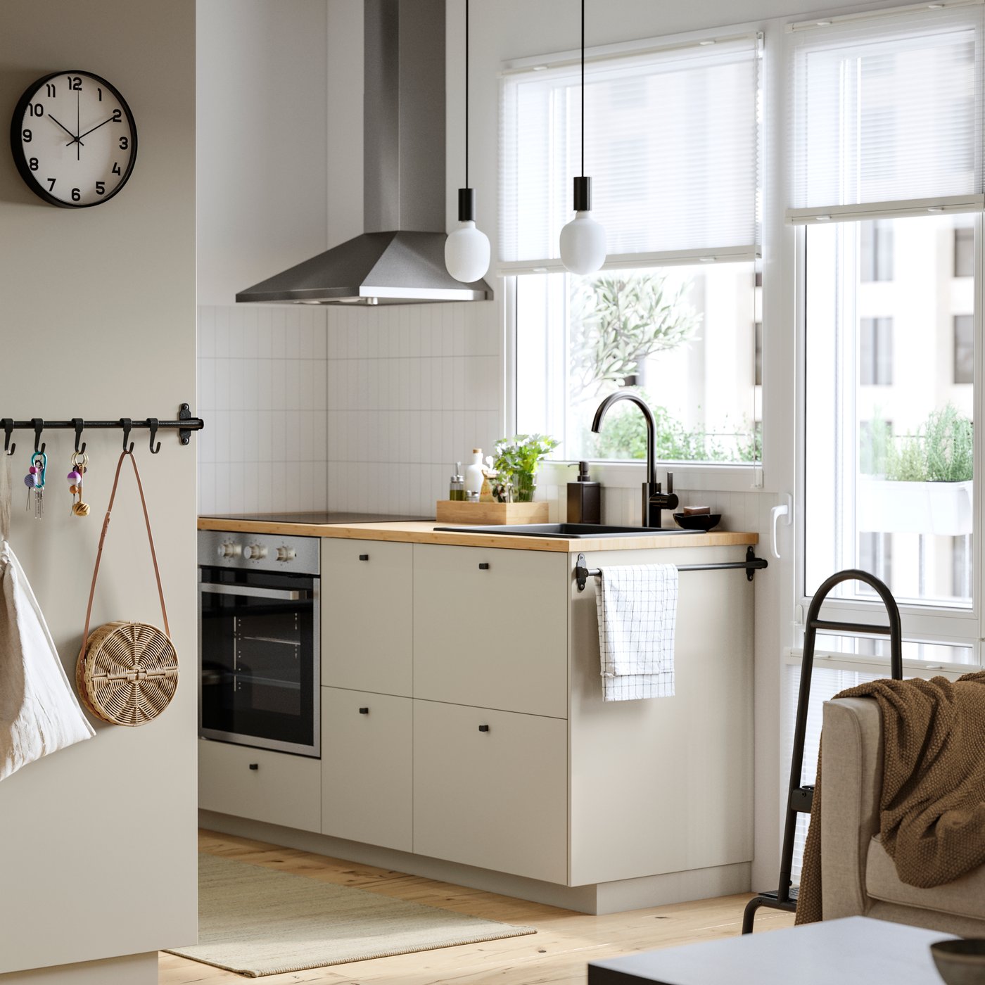 A kitchen with a window and a balcony door has beige HAVSTORP fronts and a RYTMISK wall mounted extractor hood.
