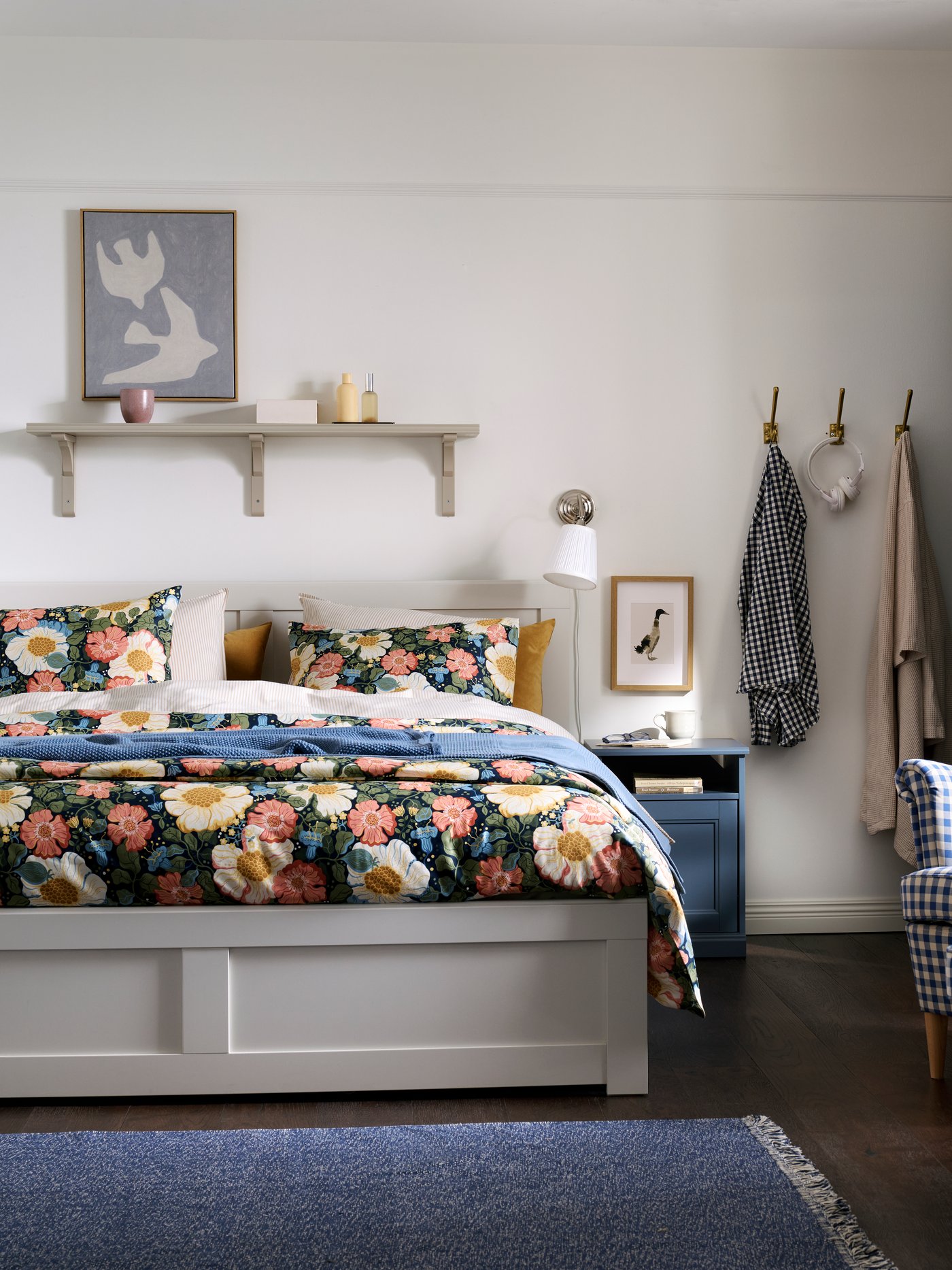 A traditional-style bedroom with a white FÅGELFJÄLLET bed, a blue FÅGELFJÄLLET bedside table and wardrobe, and floral bedding.