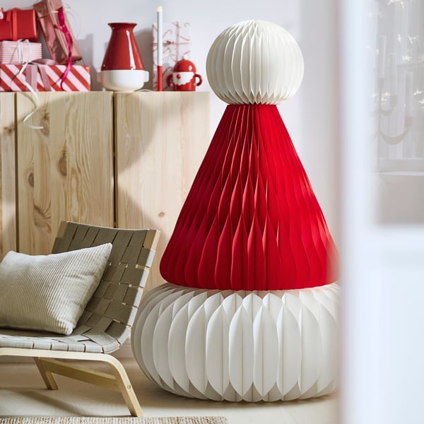 A large red and white VINTERFINT Santa Claus hat paper decoration beside an chair in front of an IVAR shelving unit.