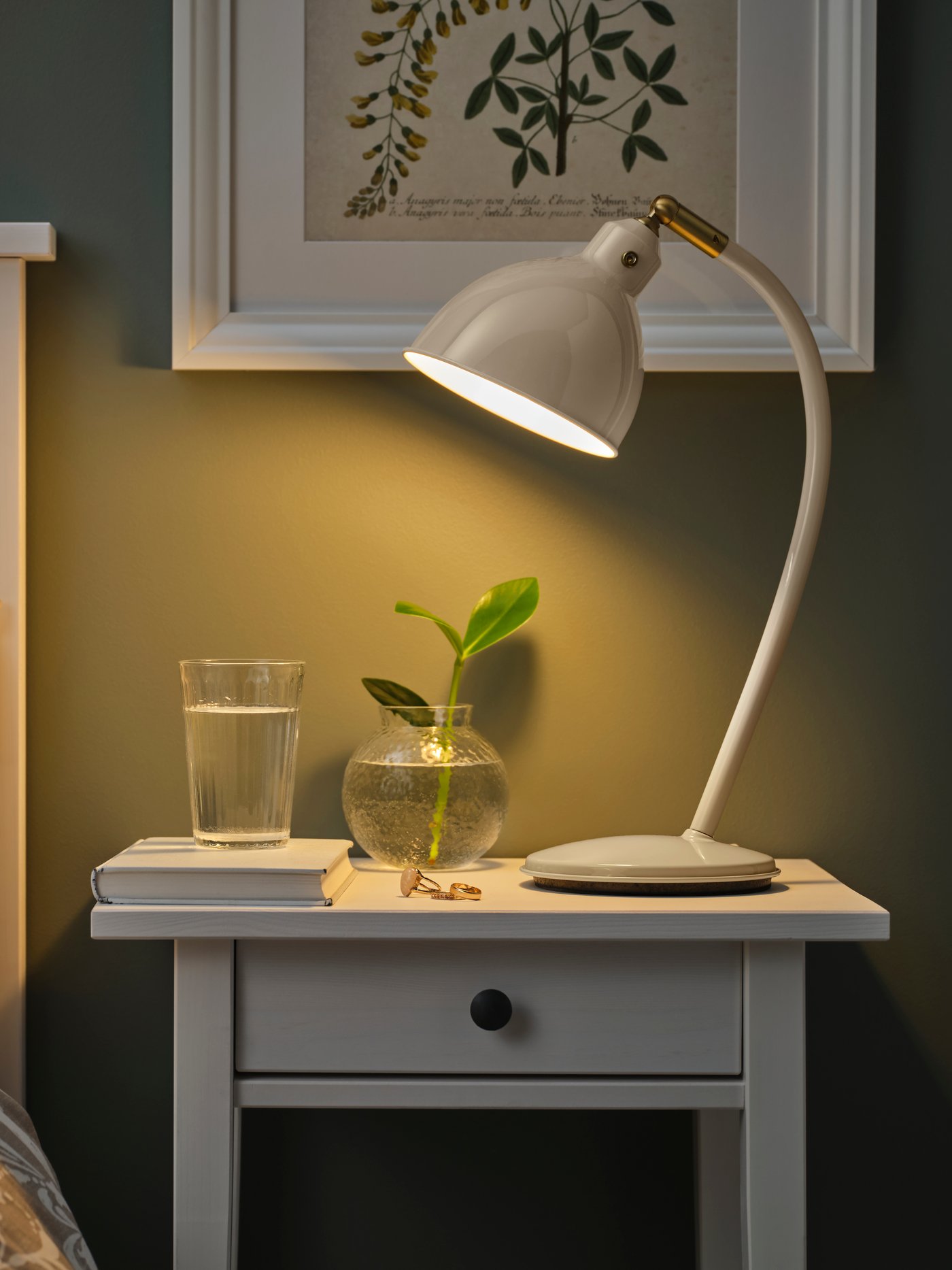 Beżowa lampa biurkowa RÖDFLIK stojąca na szafce nocnej.